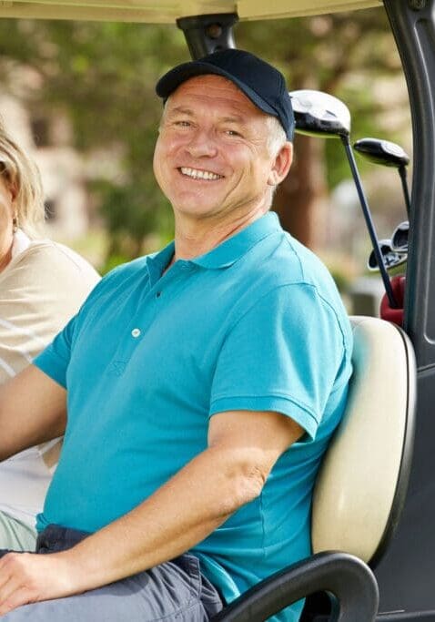 Couple ready to play golf in a golf cart.